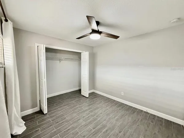 an empty room with wooden floor cabinet and windows