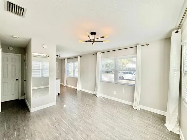 a view of an empty room with a window and wooden floor