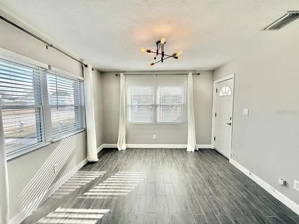 a view of an empty room with a window and wooden floor