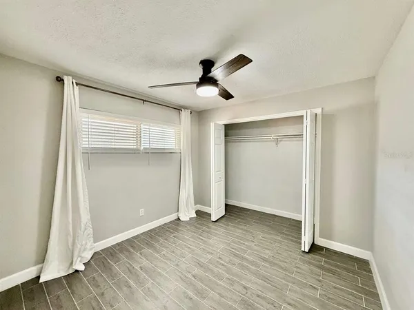 an empty room with wooden floor and ceiling fan