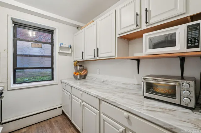 a kitchen with stainless steel appliances granite countertop white cabinets and window