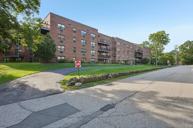 a front view of a building with garden and trees