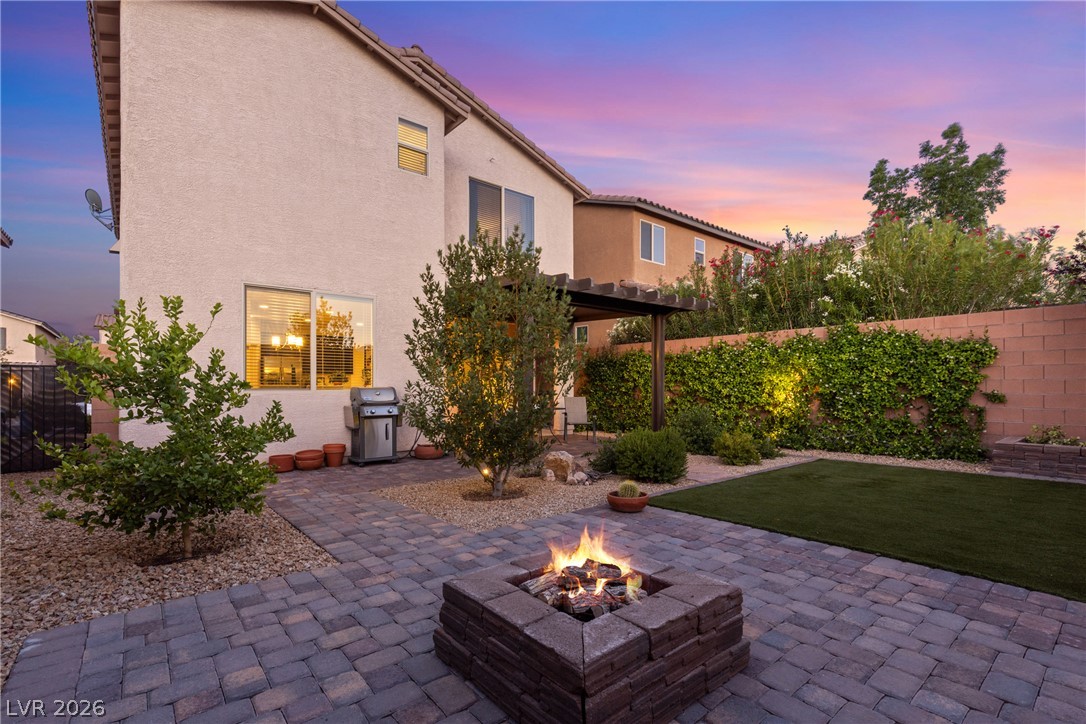 891 Earth Luster Road Las Vegas, NV 89178 - Photo 35 of 48 An inviting backyard oasis offers a built-in fire pit, paved patio, and pergola, perfect for evening gatherings.