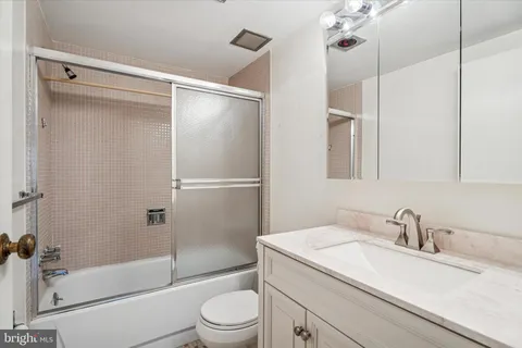 a bathroom with a granite countertop sink toilet and shower