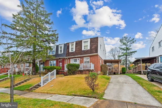 a front view of a building with garden and trees