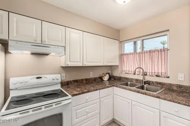 a kitchen with granite countertop white cabinets and a sink