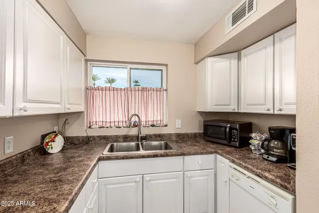 a kitchen with stainless steel appliances granite countertop white cabinets sink and window