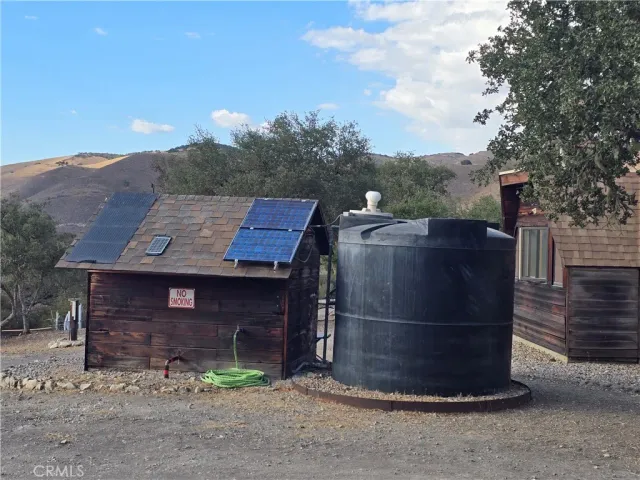 a view of a wooden house with a yard and large tree