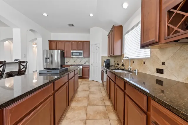 a large kitchen with stainless steel appliances granite countertop a sink counter space a stove and a sink