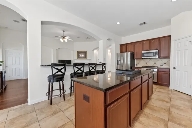 a kitchen with stainless steel appliances granite countertop a table chairs sink and cabinets