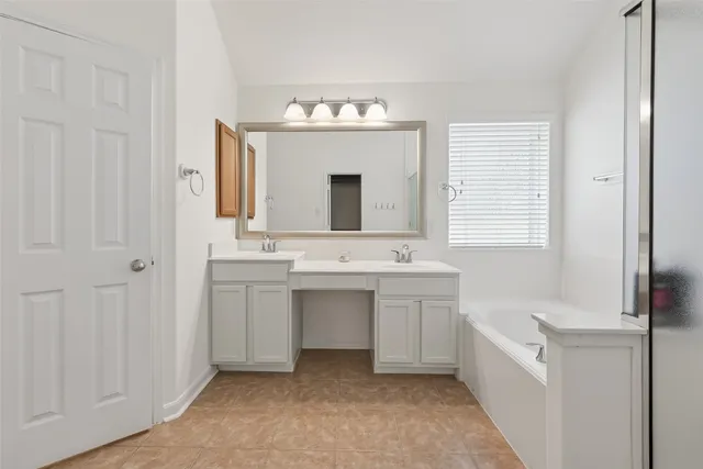 a bathroom with a double vanity sink mirror and bathtub
