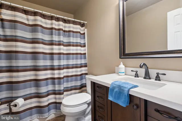 a bedroom with a bed a mirror on dresser and a chandelier