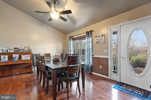 a kitchen with stainless steel appliances granite countertop a refrigerator a stove a sink dishwasher a dining table and chairs with wooden floor