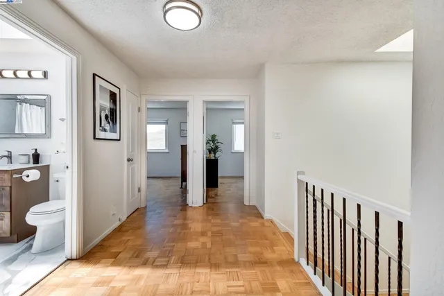 a view of a hallway with bathroom and wooden floor