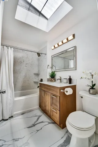 a bathroom with a granite countertop toilet sink and mirror