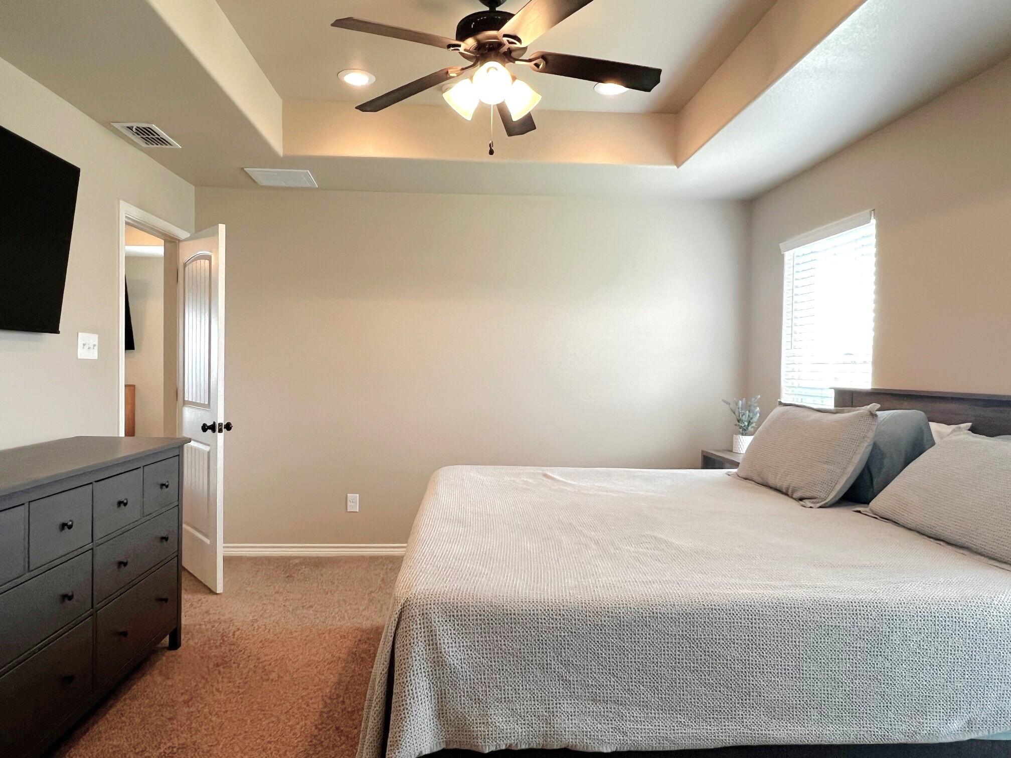 8803 10th Place Lubbock, TX 79416 - Photo 15 of 27 a bedroom with a bed and a chandelier