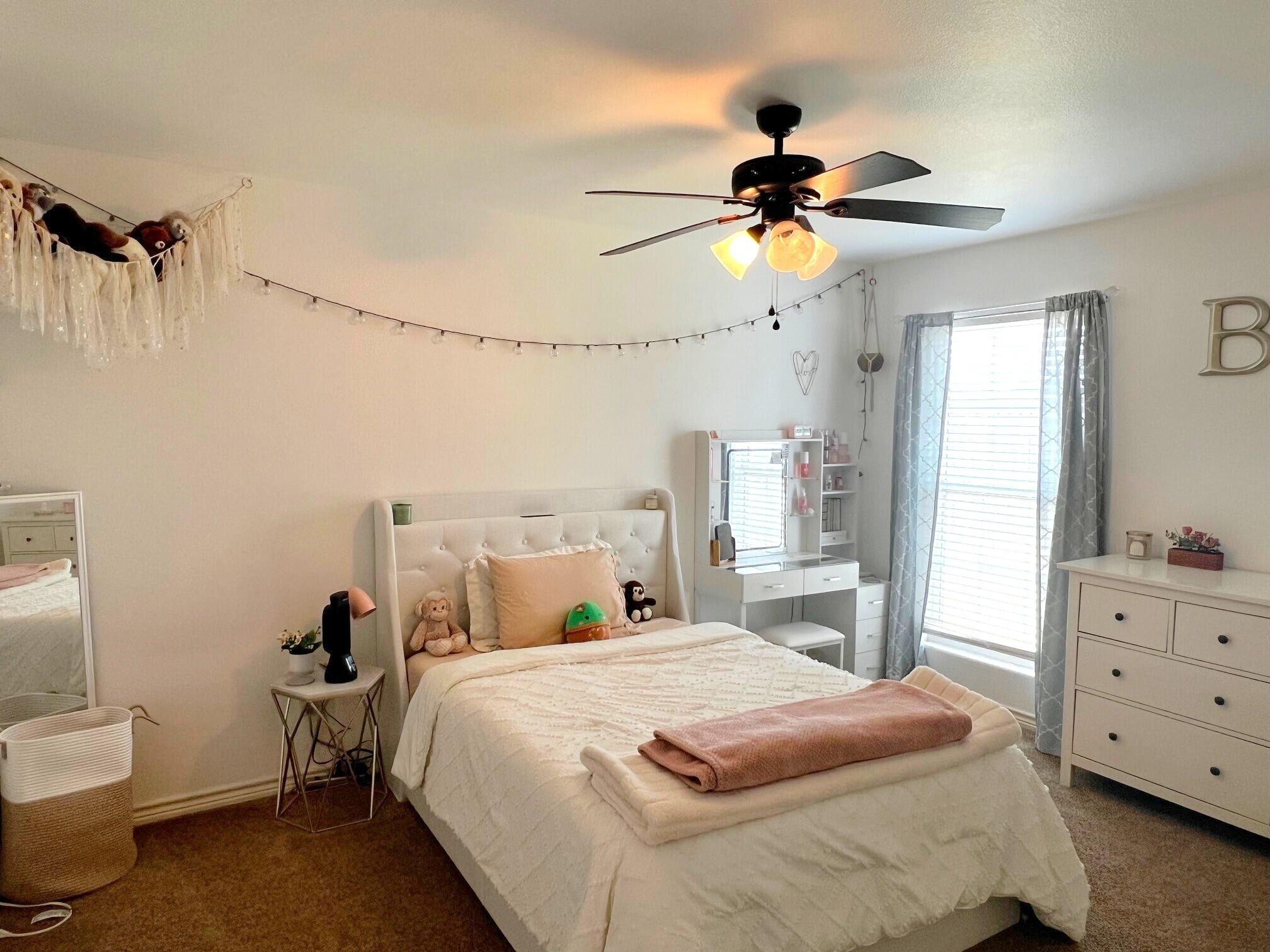 8803 10th Place Lubbock, TX 79416 - Photo 19 of 27 a bedroom with a bed and a chandelier
