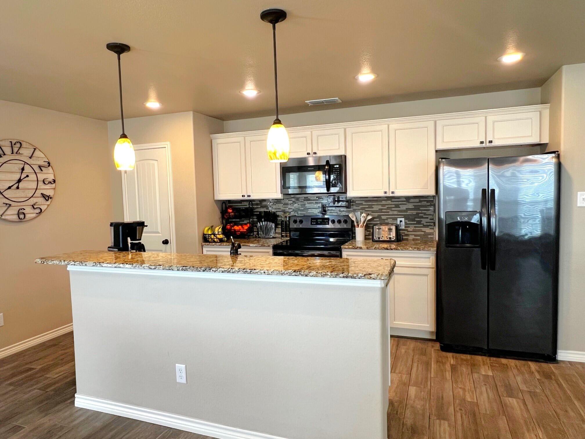 8803 10th Place Lubbock, TX 79416 - Photo 5 of 27 a kitchen with kitchen island a counter top space a sink a refrigerator and a stove