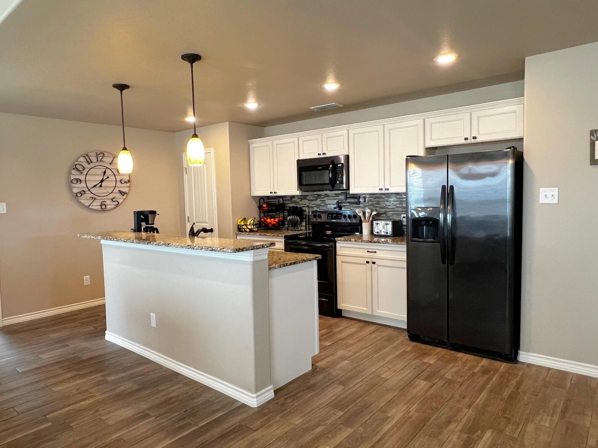 8803 10th Place Lubbock, TX 79416 - Photo 6 of 27 a kitchen with kitchen island stainless steel appliances a refrigerator a stove a sink and a chandelier