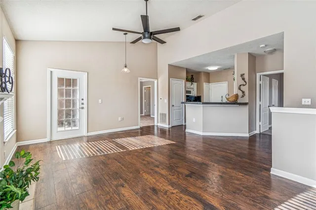 a view of an empty room with wooden floor fireplace and a window