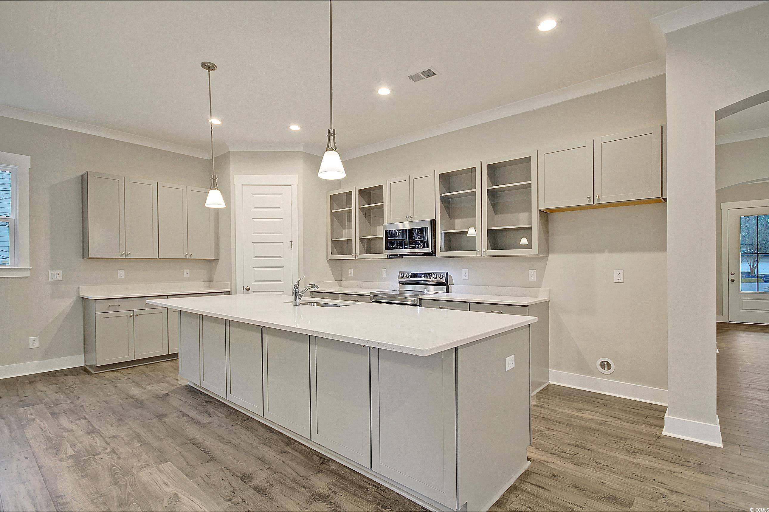 171 Pinebury Drive Georgetown, SC 29440 - Photo 4 of 30 Kitchen with glass insert cabinets, healthy amount of natural light, ornamental molding, a center island with sink, and hanging light fixtures