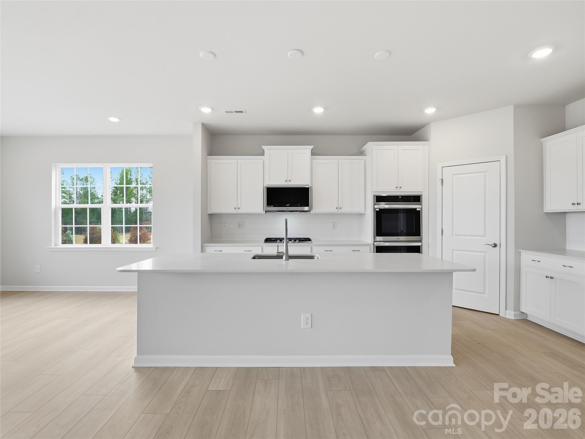 5420 Redbud Road Lancaster, SC 29720 - Photo 10 of 32 a large kitchen with stainless steel appliances a sink a stove a microwave a center island and a window