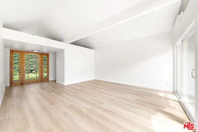 a view of an empty room with window and a kitchen
