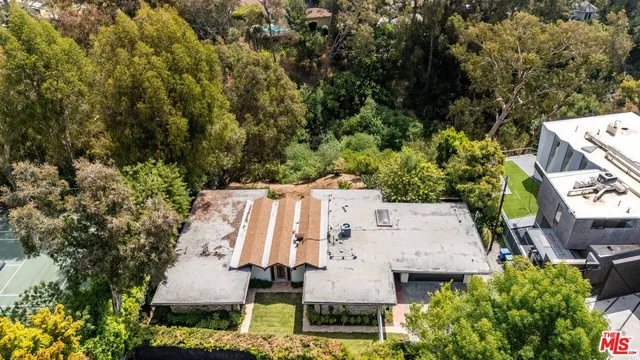 an aerial view of residential house with outdoor space and trees all around