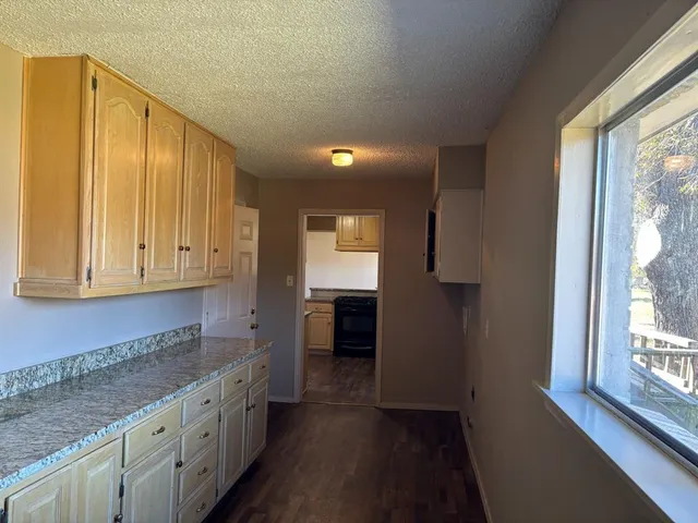 a kitchen with granite countertop a stove a sink and a refrigerator