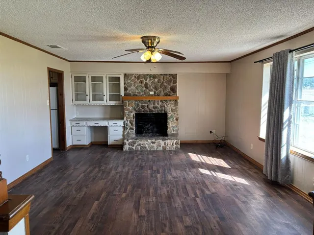 a view of an empty room with wooden floor fireplace and a window