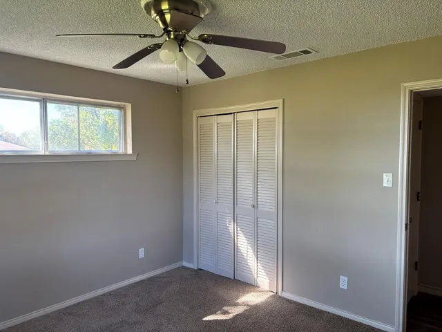 an empty room with windows and fan