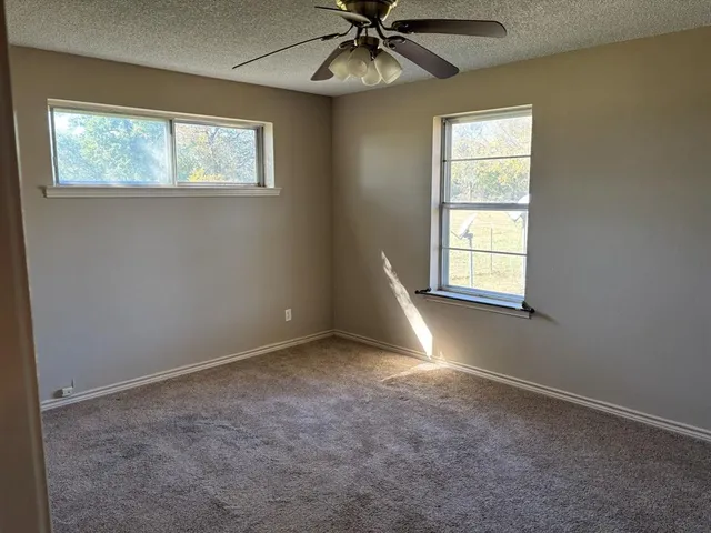 an empty room with windows and fan