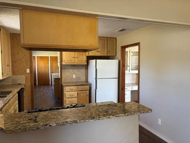 a bathroom with a granite countertop sink and a refrigerator