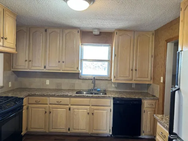 a kitchen with granite countertop stainless steel appliances white cabinets granite counter tops and a window