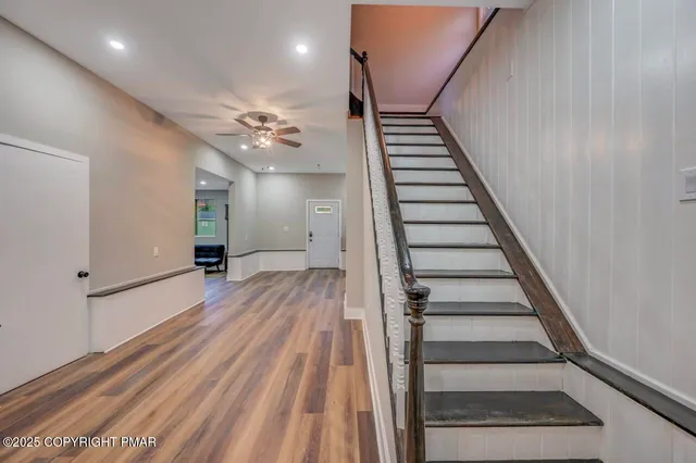 a view of a hallway with wooden floor and a bathroom