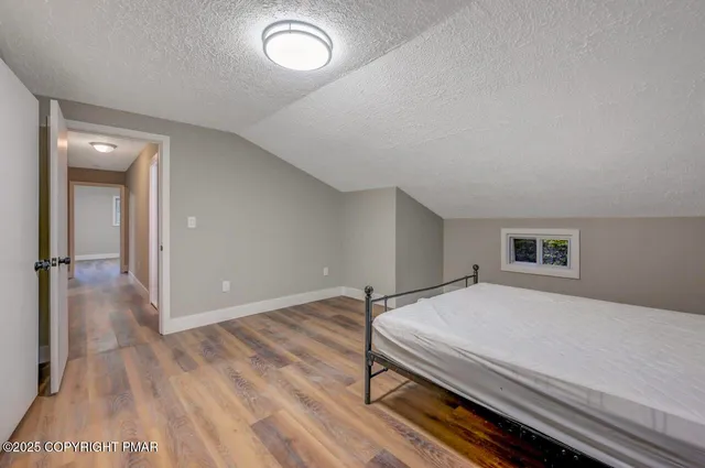 a spacious bedroom with a bed and wooden floor