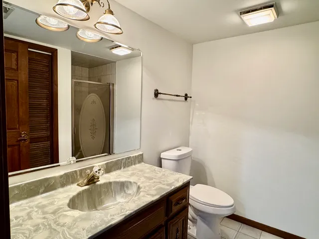 a bathroom with a granite countertop sink a toilet and a mirror