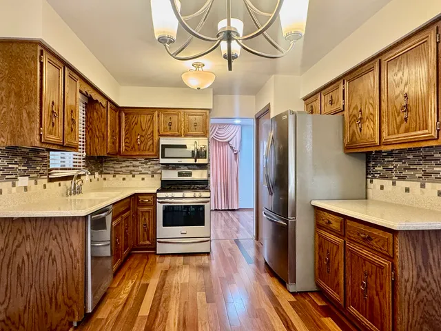a kitchen with stainless steel appliances a sink cabinets and wooden floor