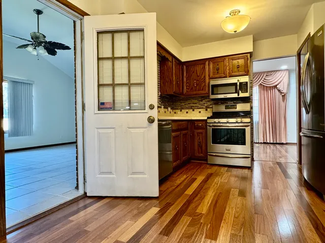 a kitchen with stainless steel appliances a stove a refrigerator and a hard wood floor