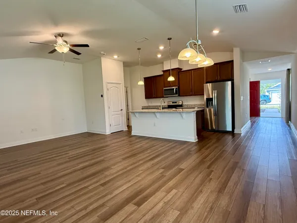 a view of a kitchen with a sink a kitchen island wooden floor and a refrigerator