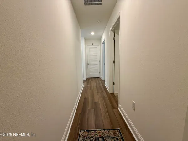 a view of a hallway with wooden floor and staircase