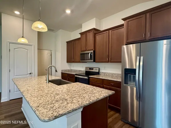 a kitchen with stainless steel appliances granite countertop a sink refrigerator and microwave