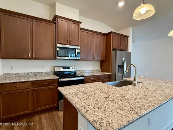 a kitchen with stainless steel appliances granite countertop a sink refrigerator and microwave