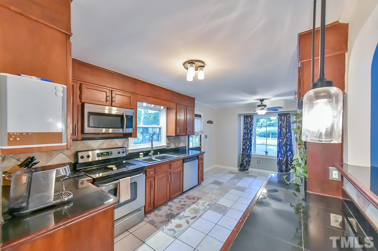 7204 Ray Road Raleigh, NC 27613 - Photo 23 of 40 a kitchen with stainless steel appliances a stove sink and cabinets