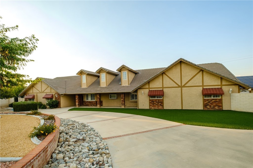 a view of a white house next to a yard with plants and large tree
