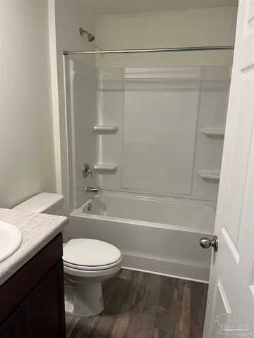 a bathroom with a granite countertop bathtub shower sink vanity and toilet