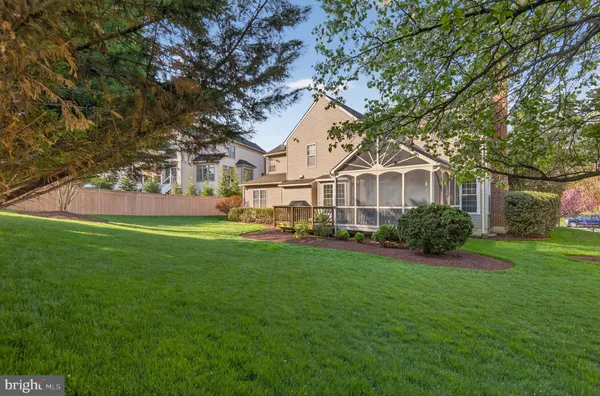 a view of a white house in front of a big yard with large trees