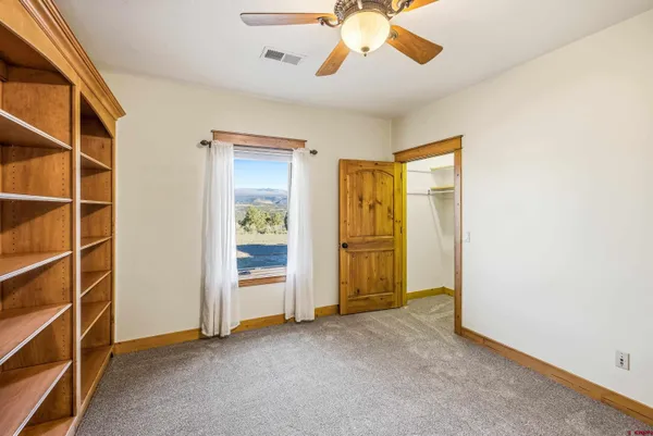 an empty room with chandelier fan and windows
