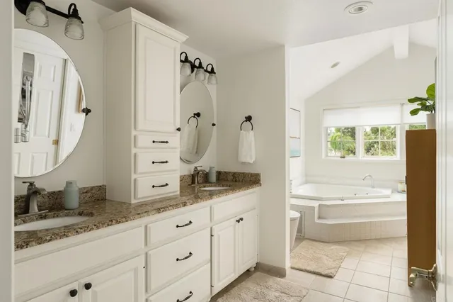 a bathroom with a granite countertop sink a mirror and a bathtub