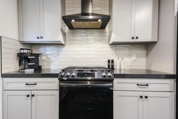 a kitchen with stainless steel appliances granite countertop white cabinets and a stove